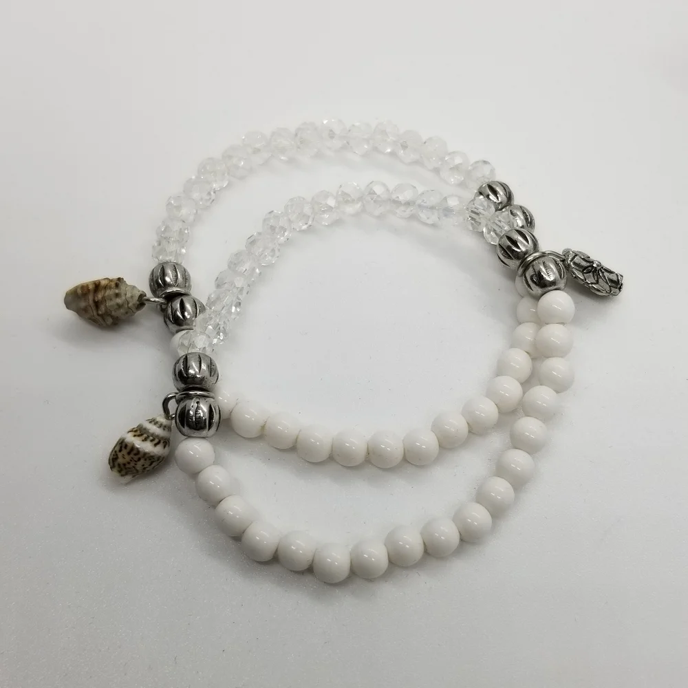 pair of white and clear stretch bracelets with shell charms